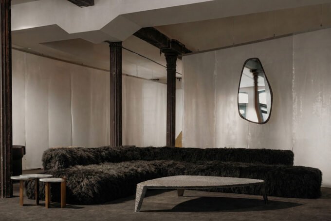 ATRA FORM Unveils a Multisensory Sanctuary in NYC: Where Ancient Craft Meets Future Wellness 9 Interior view of ATRA FORM's New York gallery, showcasing minimalist furniture and a dark, textured carpet, with a Pyramid Chair and Chronos Light Sculpture visible.