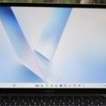 Comparison of a MacBook Neo alongside an Asus Vivobook 14 and HP OmniBook 5 laptops, highlighting their features and designs.