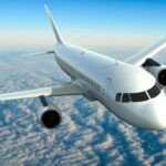 Un avion de ligne moderne en vol, avec un arrière-plan de ciel bleu et quelques nuages, symbolisant le défi de la décarbonation de l'aviation.