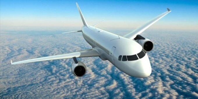 Un avion de ligne moderne en vol, avec un arrière-plan de ciel bleu et quelques nuages, symbolisant le défi de la décarbonation de l'aviation.