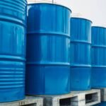 براميل نفط متراصة مع رسم بياني يظهر تراجع أسعار النفط العالمية، في إشارة إلى التقلبات الأخيرة في سوق الطاقة.