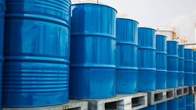 براميل نفط متراصة مع رسم بياني يظهر تراجع أسعار النفط العالمية، في إشارة إلى التقلبات الأخيرة في سوق الطاقة.