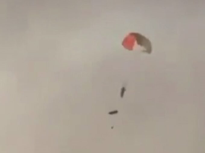 صورة لمقاتلة أمريكية من طراز F-15E تتصاعد منها النيران والدخان بعد إسقاطها فوق الكويت، مع ظهور طيارين يقفزان بالمظلات.