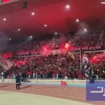 صورة بانورامية لمدرجات ملعب مراكش الكبير وهي تشتعل بحماس جماهير الكوكب المراكشي وأعلامهم الملونة وتيفوهاتهم الإبداعية.
