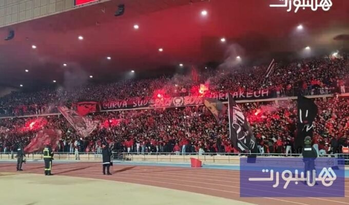 صورة بانورامية لمدرجات ملعب مراكش الكبير وهي تشتعل بحماس جماهير الكوكب المراكشي وأعلامهم الملونة وتيفوهاتهم الإبداعية.