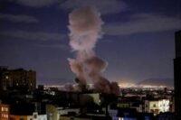 صورة جوية لمنشآت مدنية في منطقة الخليج تظهر عليها آثار هجوم أو طائرات مسيرة تحلق فوقها، تعكس التوترات الإقليمية.