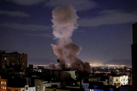 صورة جوية لمنشآت مدنية في منطقة الخليج تظهر عليها آثار هجوم أو طائرات مسيرة تحلق فوقها، تعكس التوترات الإقليمية.