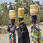 امرأة كينية في توركانا تجمع المياه من بئر جافة، رمزًا للمعاناة من الجفاف ونقص المياه.