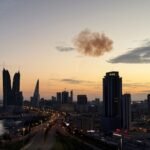 تصاعد الدخان بعد اعتراض طائرة إيرانية مسيرة فوق أبراج المنامة المالية، حيث تقع السفارة الإسرائيلية، في سياق الصراع الأمريكي الإسرائيلي مع إيران.