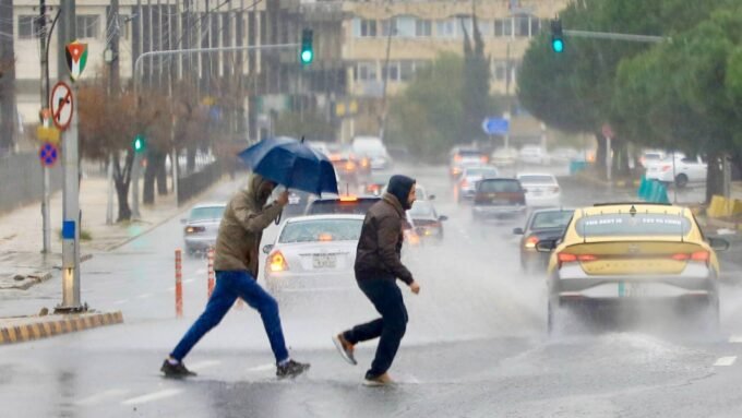 صورة تظهر أمطار غزيرة أو سيول في منطقة حضرية بالأردن مع سماء ملبدة بالغيوم.