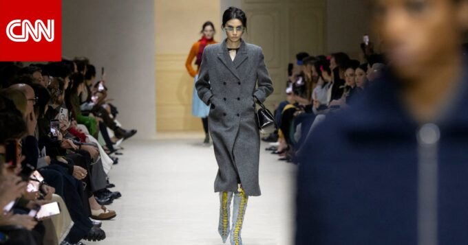 صورة لعرض أزياء فاخر لدار برادا، يظهر فيها الحضور من النخبة وبعض الشخصيات البارزة، مع التركيز على التصميمات المعروضة.