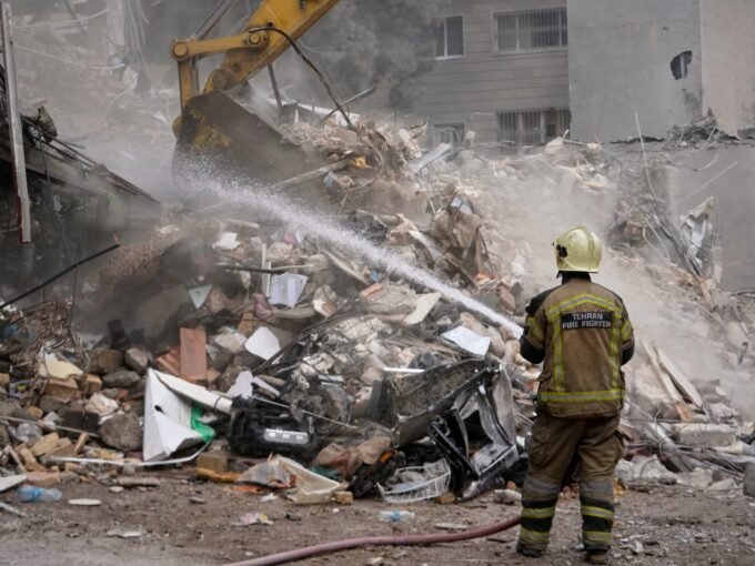 رجل إطفاء يخمد حطاماً متفحماً في مبنى سكني تعرض لهجوم أمريكي إسرائيلي في طهران، إيران، في 23 مارس 2026.