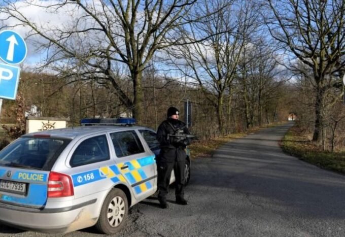 صورة لمبنى مصنع متضرر جراء حريق، مع وجود عناصر الشرطة التشيكية في محيطه.