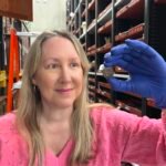 صورة مقربة لعملة معدنية قديمة ذات نقوش باهتة، مع خلفية لمتحف.