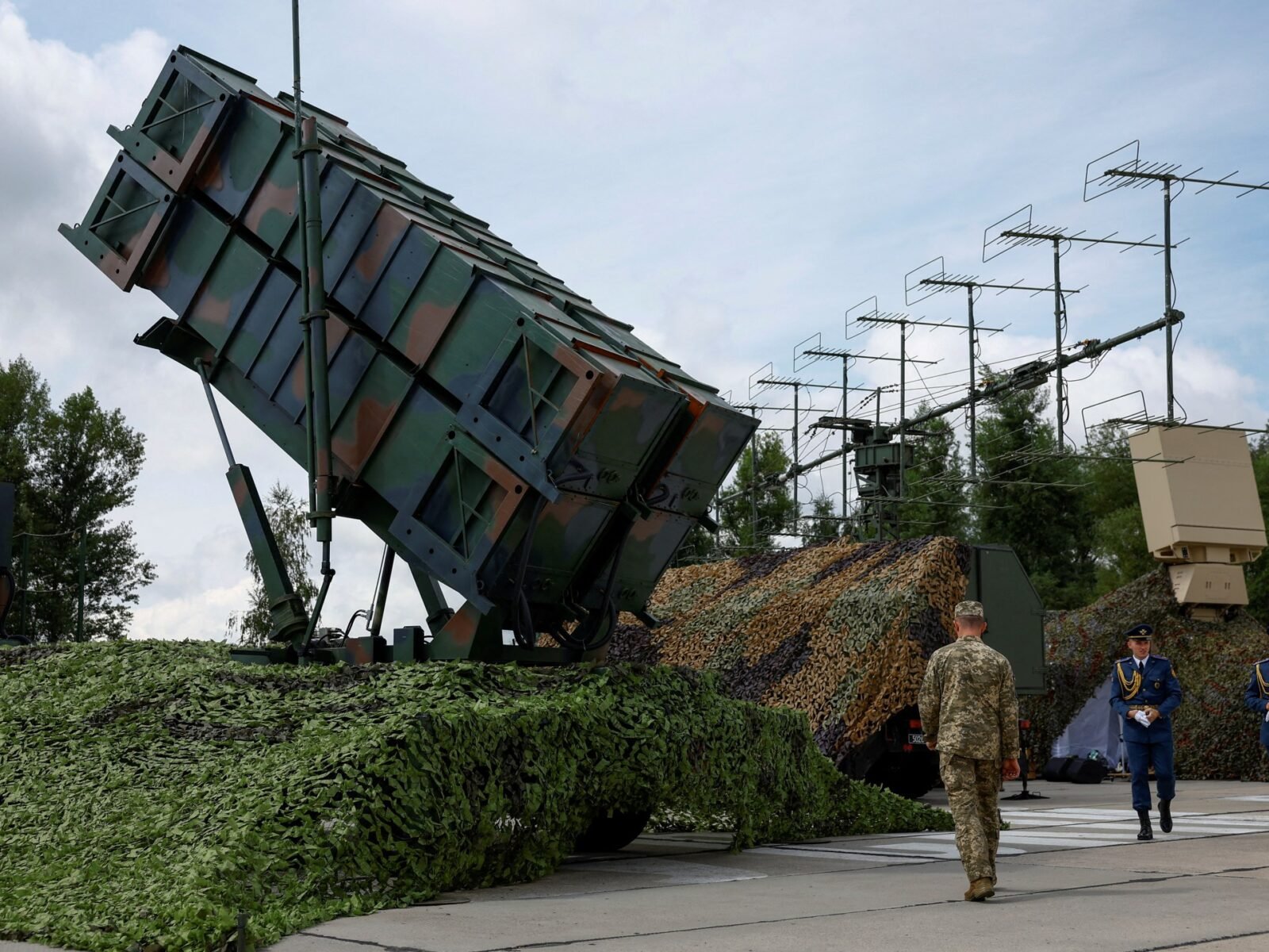 نقص صواريخ باتريوت في أوكرانيا: هل تستغل روسيا الفرصة لتكثيف هجماتها؟ 3 جنود أوكرانيون يسيرون بجانب قاذفة نظام الدفاع الجوي باتريوت في موقع غير معلن بأوكرانيا، وسط الحرب الروسية.