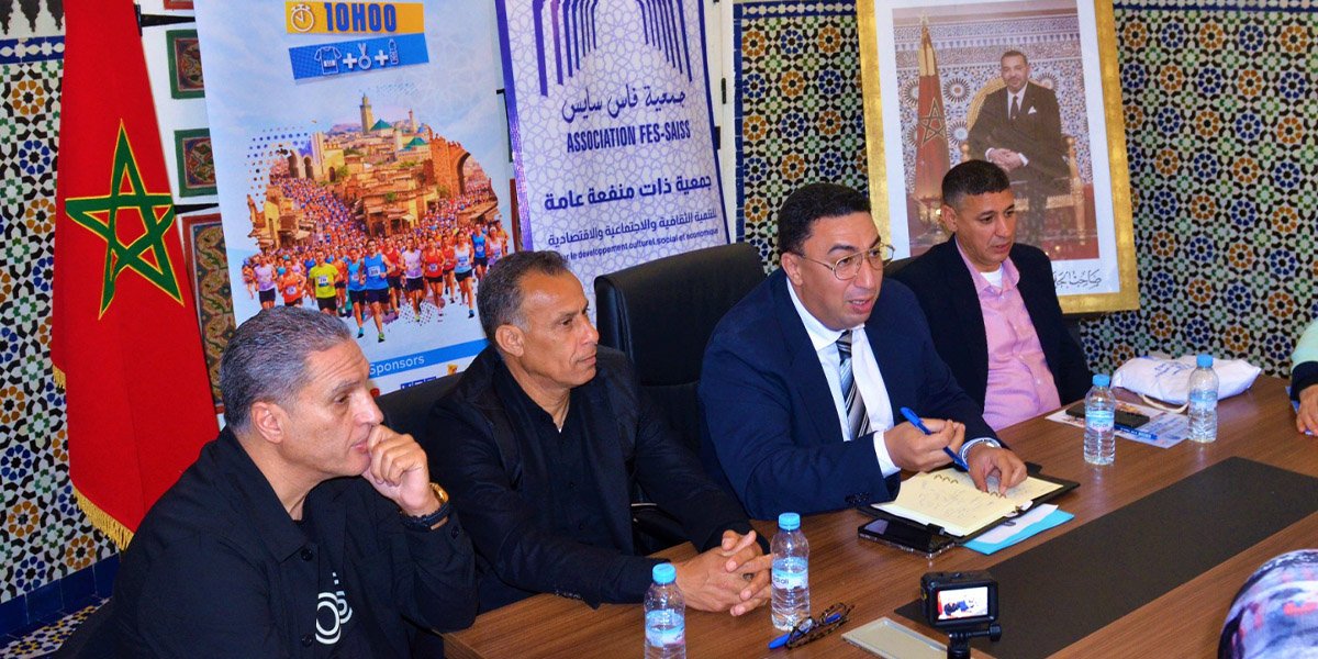 De Bab en Bab : Une Course Inédite pour Explorer la Médina de Fès 1 Vue aérienne de la médina de Fès avec des coureurs traversant ses rues étroites, longeant les remparts et s'approchant de la porte emblématique de Bab Boujloud, lors de la course 'De Bab en Bab'.