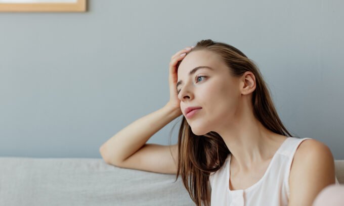 A person sitting on a couch, engrossed in watching television, with a subtle glow from the screen on their face, symbolizing passive screen time.