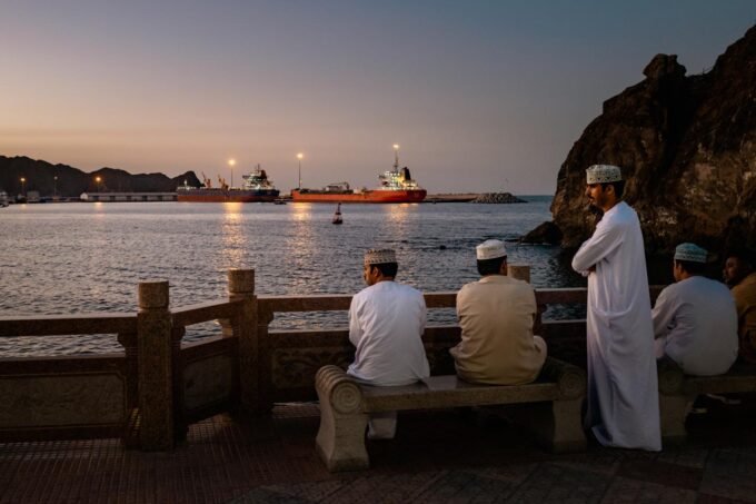 Des vraquiers et des pétroliers sont amarrés dans le golfe d’Oman, face au port de Sohar, tandis qu’une famille se retrouve pour prendre le thé près de la plage, à Shinas (Oman), le 27 mars 2026.