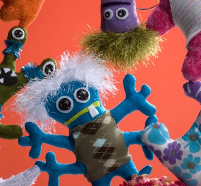 A whimsical collection of colorful, hand-sewn plush monsters, each uniquely designed with different shapes, eyes, and features, embodying the "free-range" crafting spirit.