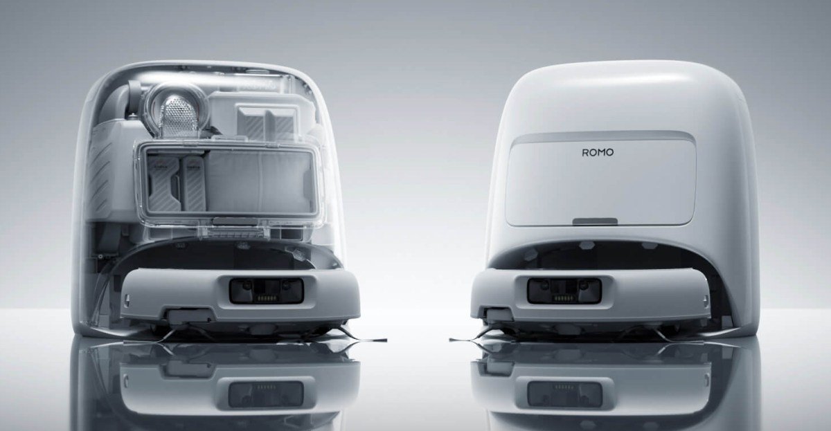 A DJI Romo robot vacuum, a sleek white disc-shaped device, on a wooden floor.