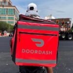 Fueling the Fleet: DoorDash Steps Up with Gas Relief for Drivers Amid Soaring Prices 8 A DoorDash delivery driver filling up a car with gas, with the DoorDash logo visible.