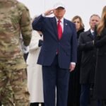 President Donald Trump salutes as a flag-draped transfer case carrying the remains of a fallen U.S. soldier is moved at Dover Air Force Base.