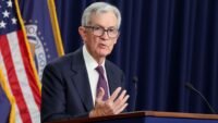 Federal Reserve Chair Jerome Powell speaking at a podium, discussing economic policy.