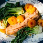 Elevate Your Plate: Ginger Salmon with Poached Apricots & Anti-Inflammatory Spices 4 Ginger-spiced salmon fillet served with bok choy and ginger-poached apricots, drizzled with chili oil.