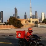 A delivery driver on a motorbike in the Gulf region, continuing their work amidst challenging circumstances.