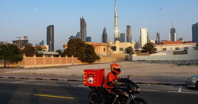 A delivery driver on a motorbike in the Gulf region, continuing their work amidst challenging circumstances.