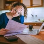 America's Debt Deluge: A Nation Grapples with Record Household Burdens 6 A person looking stressed while reviewing financial documents, with a calculator and bills on a table.