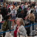 Travelers queueing in a long security line at a busy airport checkpoint, highlighting the impact of staffing shortages.