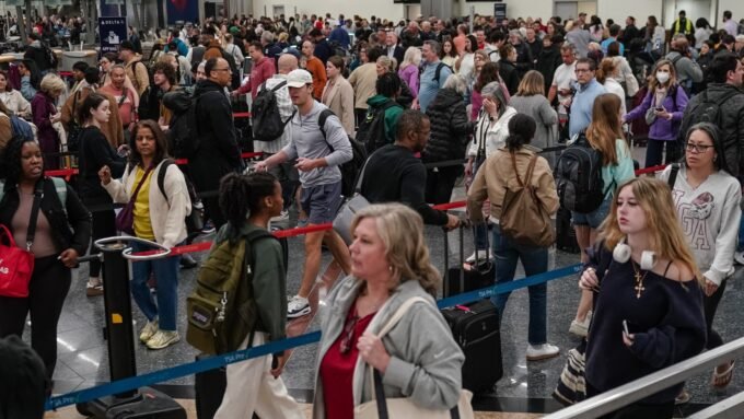 Travelers queueing in a long security line at a busy airport checkpoint, highlighting the impact of staffing shortages.