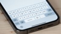 An iPhone screen displaying a keyboard with text being typed, symbolizing the upcoming iOS 26.4 keyboard fix.