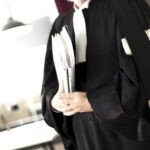 Une balance de justice stylisée, symbolisant l'équilibre et la profession d'avocat, avec un arrière-plan flou de documents juridiques et de mains en discussion, évoquant les tensions et les négociations autour du projet de loi.