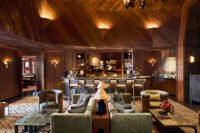 Interior view of L’Apogée Courchevel dining space, showcasing Kelly Wearstler's Alpine Brutalism design with textured wood and stone elements.