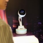Lenovo's AI Workmate: The Robot That Wants to Revolutionize Your Desk (and Maybe Your Patience) 6 Lenovo AI Workmate Concept robot projecting an image onto a desk, with a hand signing a document.