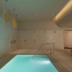 Interior view of Lore Bath House showing the cold plunge pool and sauna area with warm lighting and natural materials.