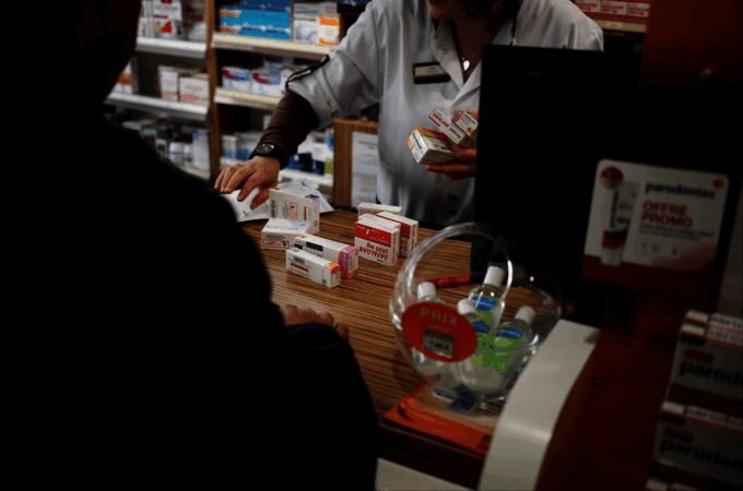 Une pharmacie marocaine avec des médicaments et un pharmacien, symbolisant le débat sur l'ouverture du capital des officines.