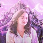 Nabyla Maan sur scène lors d'un concert, micro en main, avec des musiciens en arrière-plan, dans une ambiance lumineuse et chaleureuse.