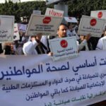 Une pharmacie marocaine traditionnelle avec un pharmacien en blouse blanche discutant avec un patient, symbolisant la proximité et le service de santé essentiel.