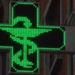 Pharmaciens en blouse blanche manifestant devant une pharmacie, avec des pancartes exprimant leur opposition à l'ouverture du capital des officines. L'image est symbolique de la mobilisation du secteur de la santé.