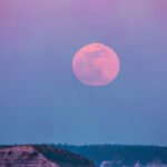 A vibrant full pink moon glowing in a night sky, symbolizing balance and new beginnings for relationships.