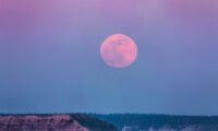 A vibrant full pink moon glowing in a night sky, symbolizing balance and new beginnings for relationships.