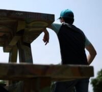 A young person looking intently at a screen, possibly a smartphone or computer, with abstract financial graphs or betting interfaces in the background, symbolizing online prediction markets and youth engagement.