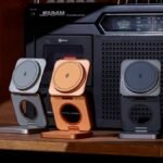 A compact, foldable 3-in-1 wireless charger powering an iPhone, Apple Watch, and AirPods simultaneously on a clean surface.