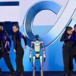 Le robot humanoïde de Honor effectuant un salto arrière sur scène lors du MWC 2026, avec le PDG James Li à ses côtés.