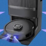 Shark PowerDetect UV Reveal robot vacuum with blue UV light activated, cleaning a hard floor.