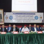 Vue aérienne d'un paysage aride du Souss-Massa avec un petit barrage ou un lac collinaire en construction, symbolisant les efforts de développement et de gestion de l'eau.