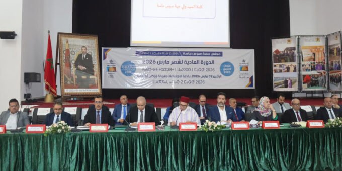 Vue aérienne d'un paysage aride du Souss-Massa avec un petit barrage ou un lac collinaire en construction, symbolisant les efforts de développement et de gestion de l'eau.